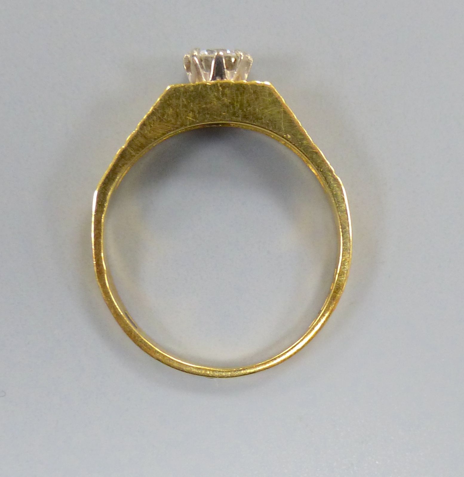 A modern 18ct gold and solitaire diamond ring, with textured shoulders, size N, gross 2.9 grams,